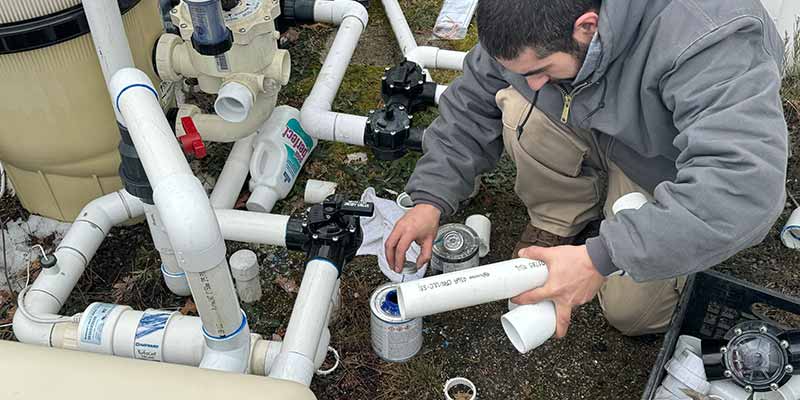 man repairing pool plumbing